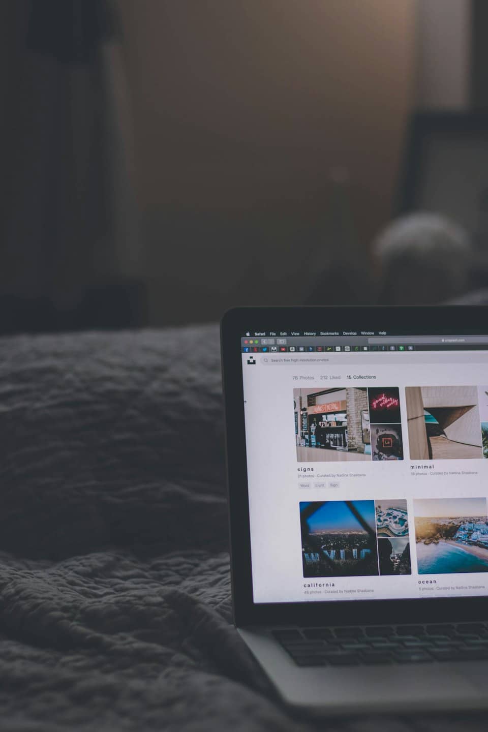 Computer portatile aperto su lenzuola grigie che mostra un sito web di fotografia.